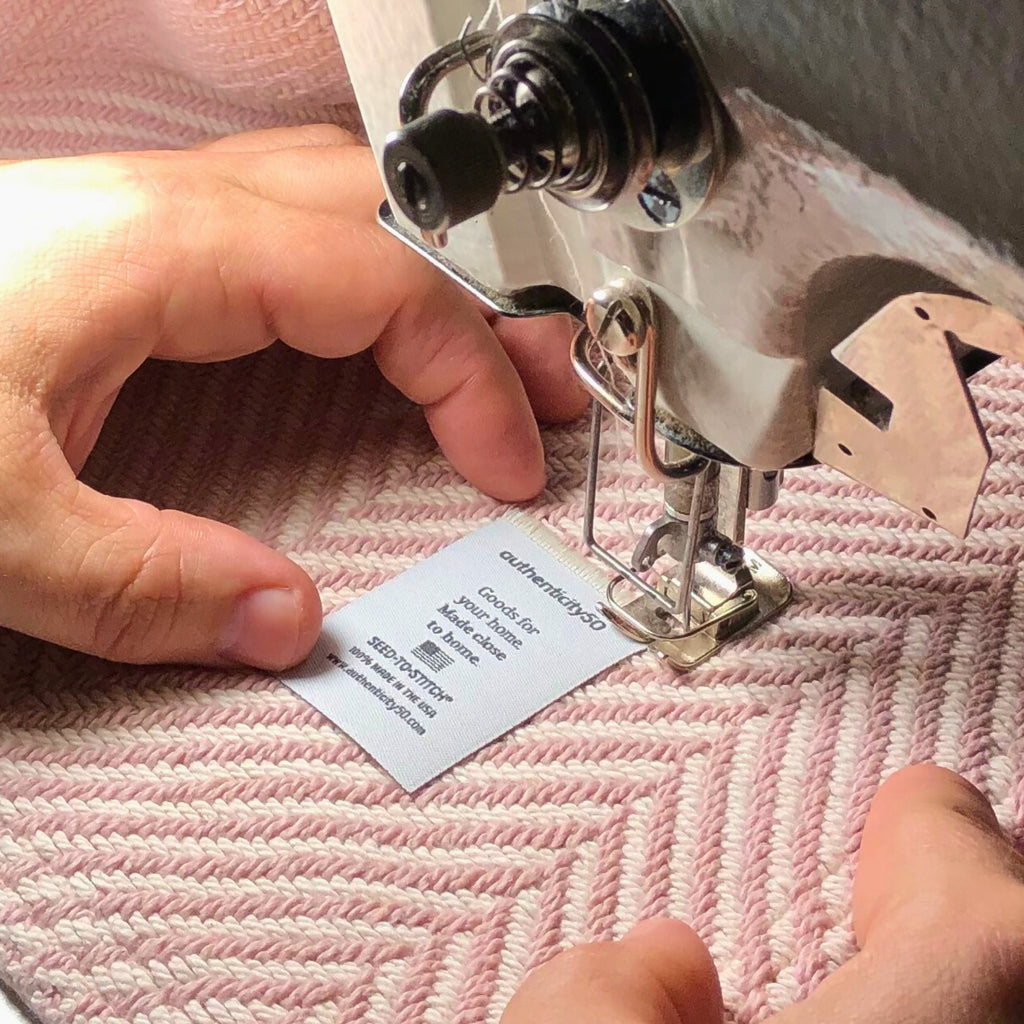 worker sewing a "seed-to-stitch" label on a heritage blanket