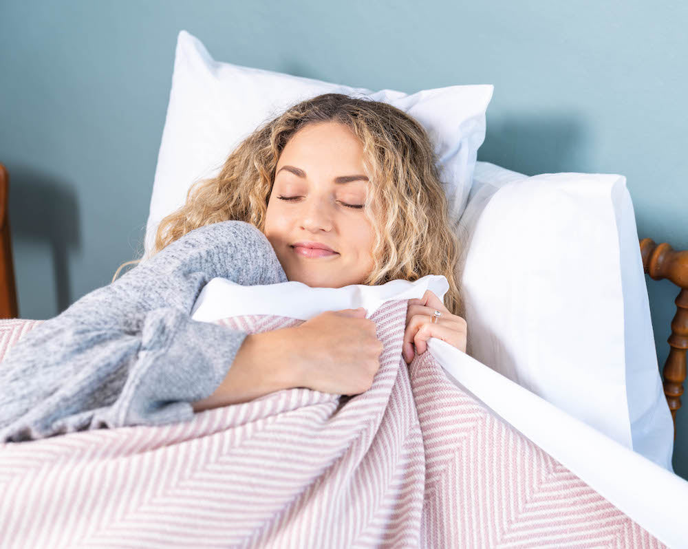 woman cuddling with cotton heritage blanket from Maine
