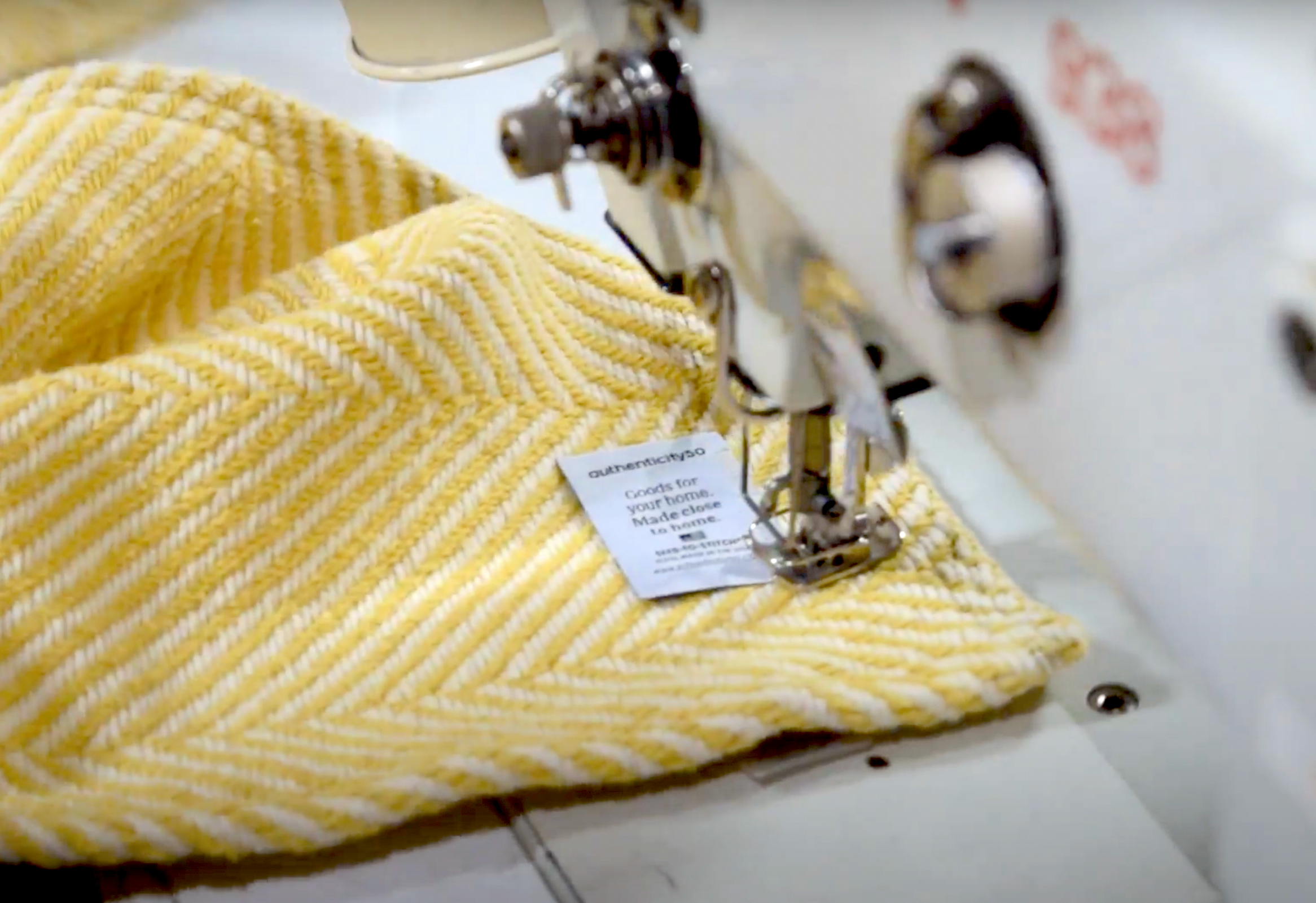 Sewing an Authenticity50 made in usa product tag onto a prairie yellow Heritage Blanket